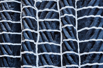 Close-up of a wall of black fired braided bricks with white joints, pattern, texture or background, abstract