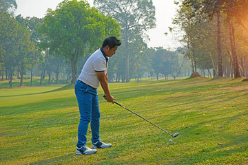 Golfer playing golf in the evening golf course, on sun set evening time.