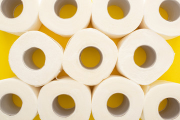 top view of white toilet paper rolls on yellow background
