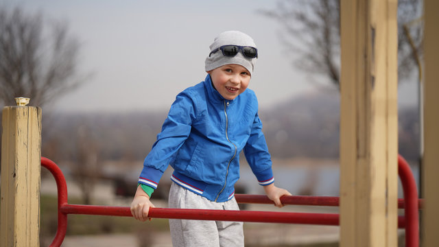 The boy does exercises on parallel bars in the fresh air in the park