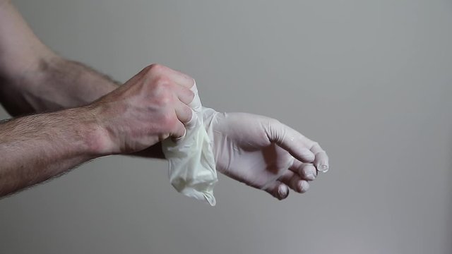 A closeup of a mans hands taking of latex gloves. 24FPS HD.
