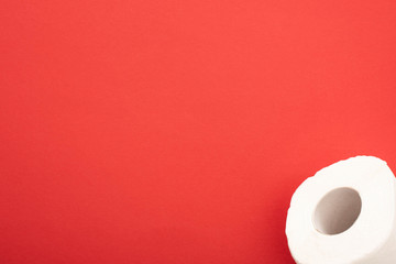 top view of white toilet paper roll on red background with copy space