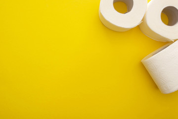 top view of clean toilet paper rolls on yellow background with copy space
