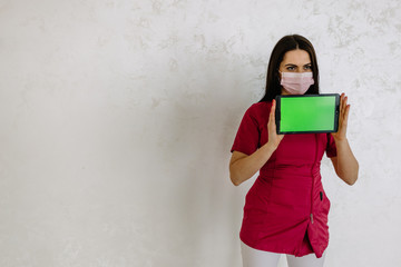 Beautiful Asian woman doctor showing the empty screen tablet and pointing her fingers to the screen close up, Empty green screen tablet background.