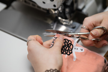 The young dressmaker cleverly cuts unnecessary threads from the fabric intended for protective masks.