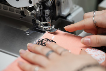 A young schoolgirl learns to sew face masks during a pandemic on an overlock sewing machine.