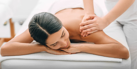 Obraz na płótnie Canvas Mixed race woman enjoying a back massage, time weekend on spa resort. mixed race woman relaxes while back massage