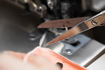 The young dressmaker cleverly cuts unnecessary threads from the fabric intended for protective masks.