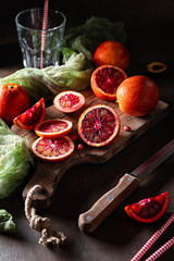 Fresh sliced blood oranges on a wooden cutting board. Low key. Dark mood.