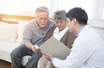 Obraz premium Young caucasian doctor man talking result of examination on tablet to senior elderly old retirement asian woman with old man take care her beside.healthcare and medical concept.