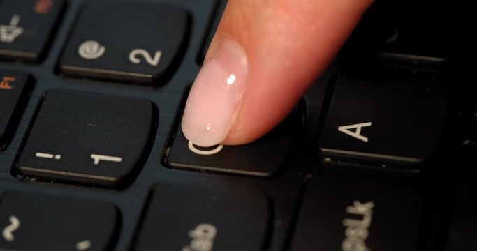 Black keyboard and a girl presses Q button. English letters. Slow-mo and girl has a pink nail polish.