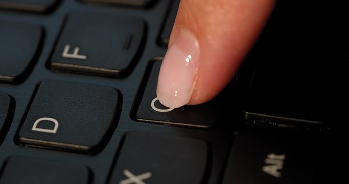 Black keyboard and a girl presses C button. English letters. Slow-mo and girl has a pink nail polish.