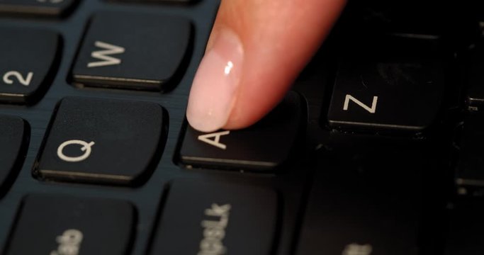 Black keyboard and a girl presses A button. English letters. Slow-mo and girl has a pink nail polish.