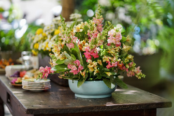 Colorful flower arrangements are set up on a wooden table.