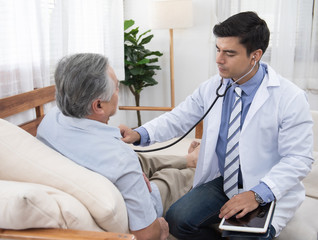 Caucasian doctor sit on chair check asian senior elderly old man heart beat lay down on sofa at...