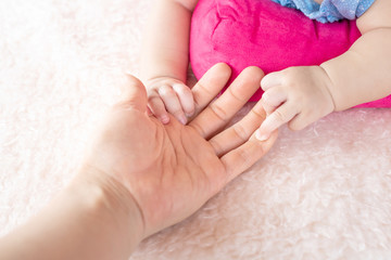 Asian Female hand holding  newborn baby hand. Mom with her child. Maternity, family, birth concept.