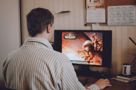 Back view of adult Man gamer using computer for playing online role-playing game World of Warcraft at home. Games for adults in Self Quarantining, Social Distancing.