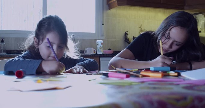 Hermanas dibujando en la mesa de la cocina 