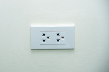 White wall socket on wall, electric socket with one button, Power outlet on white wall.