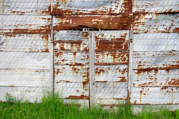 Rusty metal wall with grass at the bottom