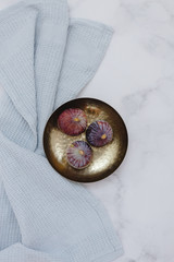 Fresh figs on gold bowl marble background