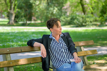 Attractive stylish woman waiting on a park bench