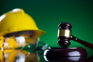 Labour law and builiding law concept.  Gavel and yellow crash helmet on the shining lawer desk.