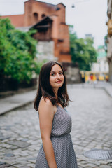 Smiling beautiful girl walking in the city. Brunette girl in summer dress on city tour.