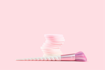 Tender pink monochrome feminine makeup tools and accessories. Unicorn blush brush and stack of sponges on candy pink. Birthday beauty cosmetics blogger advert background concept. Copy space