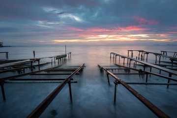 Old metal sea pier for boats at sunset with long exposure water near Burgas, Bulgaria. Black sea landscape