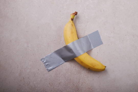 Banana Duct Taped To The White Wall. Conceptual Photo.