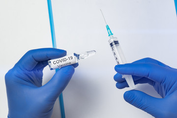 Microbiologist holding syringe and ampoule with vaccine for coronavirus. Covid-19 infectious disease