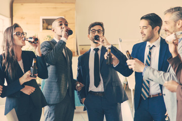 Relaxed office managers drinking beer in office. Cheerful young people relaxing after hard work. Relaxation concept