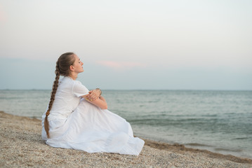 Fototapeta na wymiar Young beautiful woman sitting on sandy beach against sea and dreams. keep calm