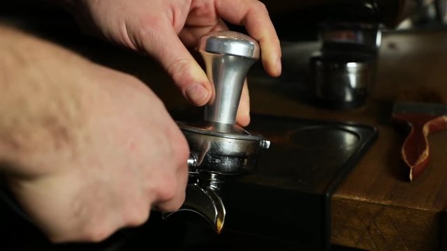 Close-up of a vintage barista making ground coffee with tamping fresh coffee. SLOMO
