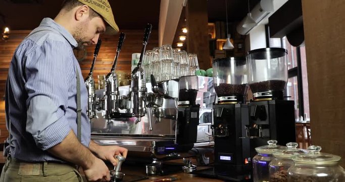 Vintage barista at work. The process of making coffee. Nice young man with a beard. Preparing cups of espresso on an authentic Italian coffee machine at a vintage coffee shop.