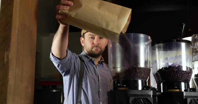Medium shot of a vintage barista man doing coffee beans in a coffee grinder.