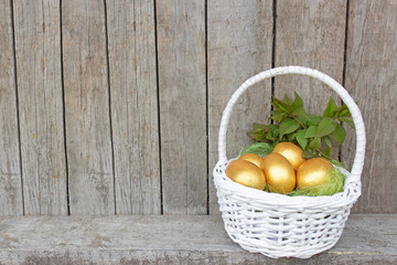 Easter, Golden eggs in a white basket. Conceptual rustic style