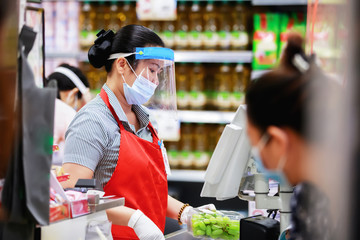female supermarket cashier in medical protective mask working at supermarket