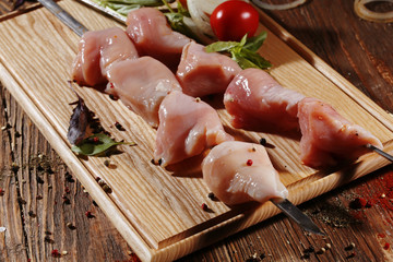 Pickled raw meat lies on a light board with tomatoes cherry, red pepper, basil, garlic and seasoning.
