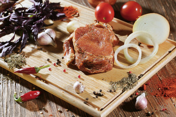 Pickled raw meat lies on a light board with onions, tomatoes cherry, red pepper, garlic and seasoning.