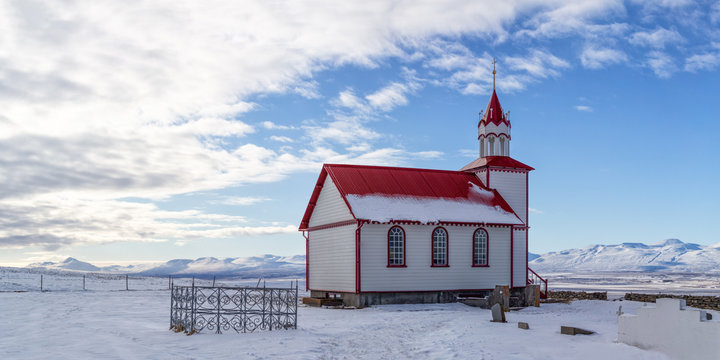 icelandic church red and white in the snow with blue sky and clouds 