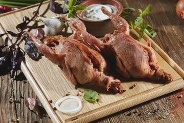 Pickled raw quail lies on a light board with white sauce, basil and seasoning.
