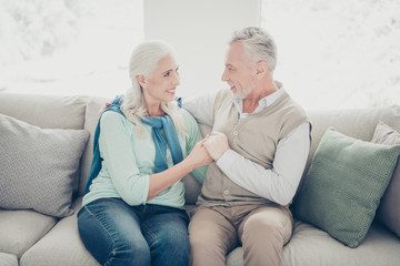 Photo of two pretty aged people pair holding arms emotionally look eyes sitting cozy sofa indoors