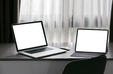 Fototapeta premium Mockup blank screen laptop and tablet with keyboard on wooden counter table in living room.