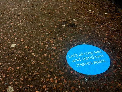 A Blue Sign On A Pavement Indicates Where People Should Stand To Keep Themselves And Others Safe By Social Distancing Two Metres Apart In National Emergency Against Coronavirus. Covid 19.Image