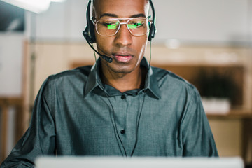 Concentrated call center operator talking with client. Front view of thoughtful call center...