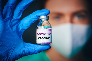 Coronavirus Covid-19 Protection and Vaccine. Female doctor, protect mask, portrait, Medicine bottle for injection medical glass vials for vaccination. Tittle "Covid-19 Vaccine" on the medical bottle