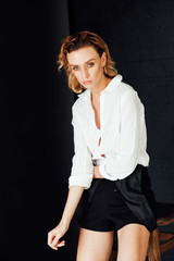 Portrait of a beautiful fashionable blonde woman in black shorts and white shirt © dmitriisimakov