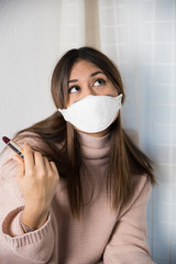 A teenager with a protective mask thinking how to apply a lipstick
